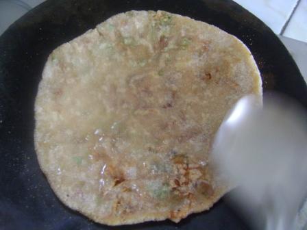 After 20 seconds, flip it again. Now spread Oil/Ghee on this side of flat-bread. Keep on cooking by flipping and applying Oil/Ghee, till it gets golden brown from both sides.